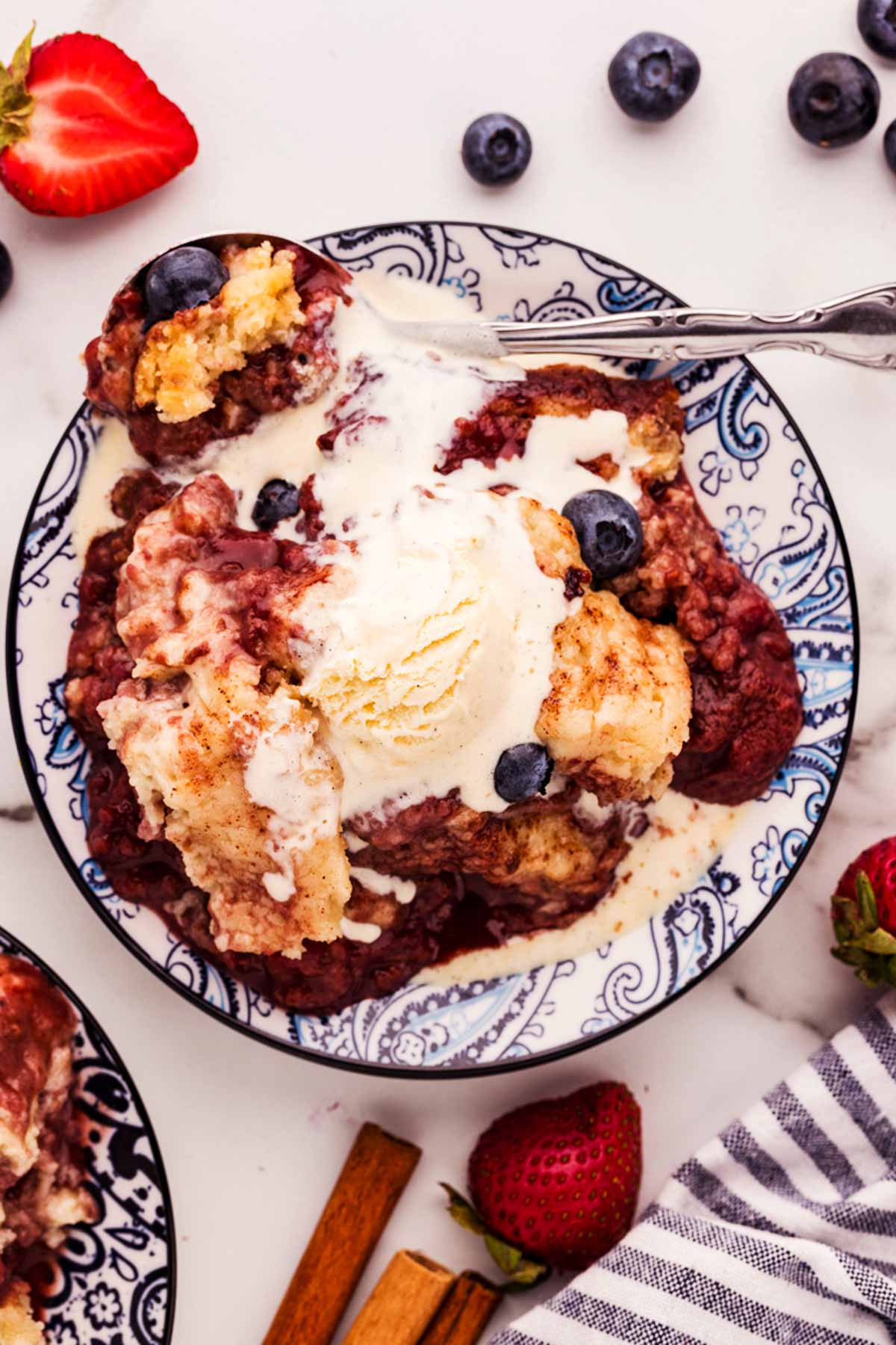 serving a plateful of berry cobbler with ice cream