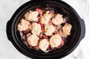 uncooked slow cooker berry cobbler sprinkled with cinnamon sugar