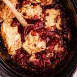 spooning up berry cobbler from the slow cooker