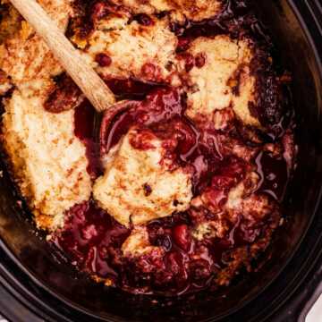 spooning up berry cobbler from the slow cooker
