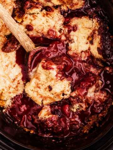 spooning up berry cobbler from the slow cooker