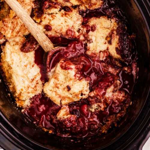 spooning up berry cobbler from the slow cooker