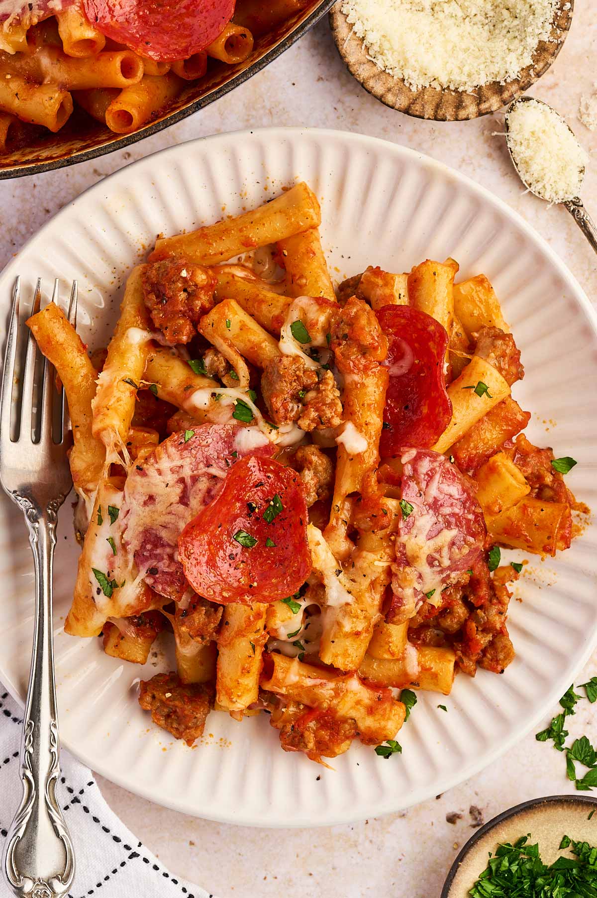 serving pizza baked ziti with parsley and parmesan