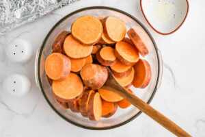 sweet potato slices being tossed with seasoning