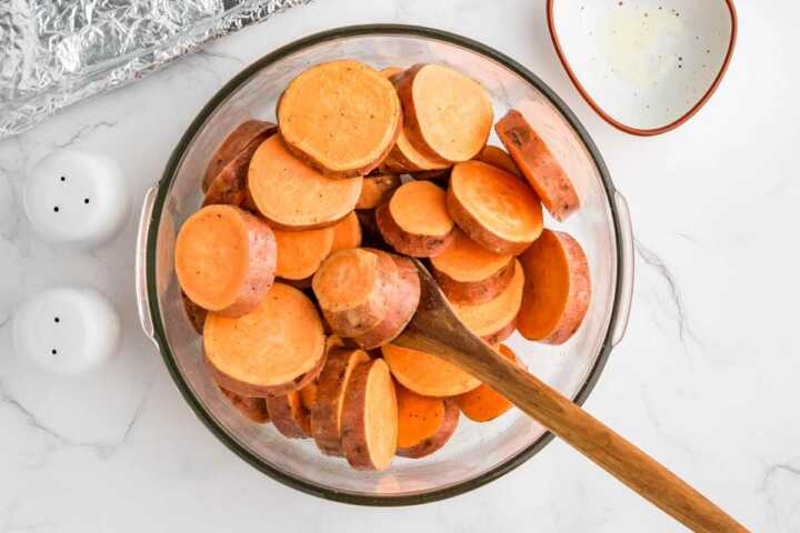 sweet potato slices being tossed with seasoning