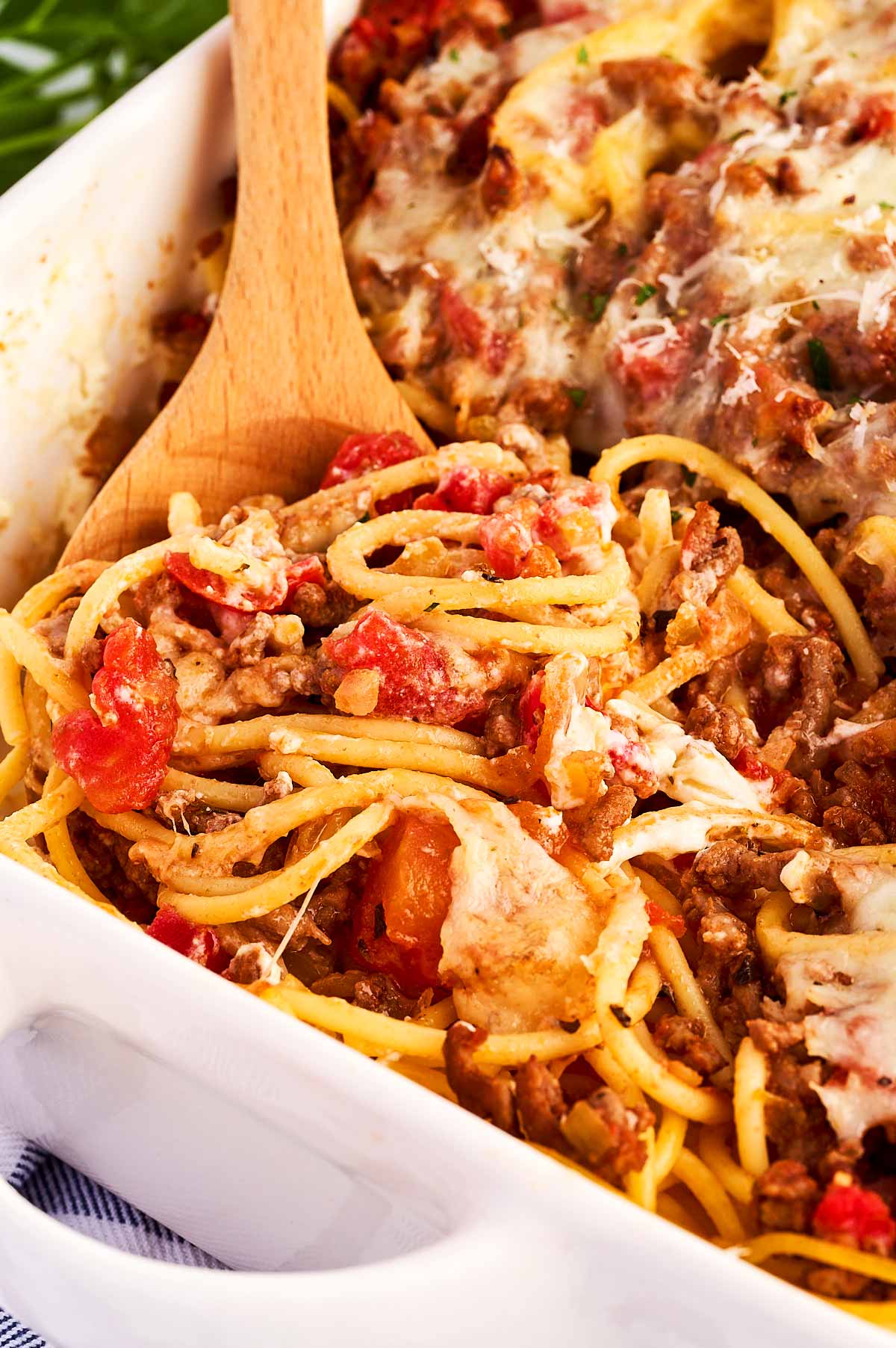 scooping up spaghetti casserole with a wooden spoon