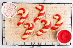 sprinkling candy cane cookies with decorating sugar and chopped candy canes