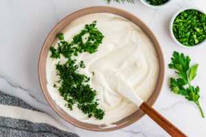 Folding herbs into dill dip.