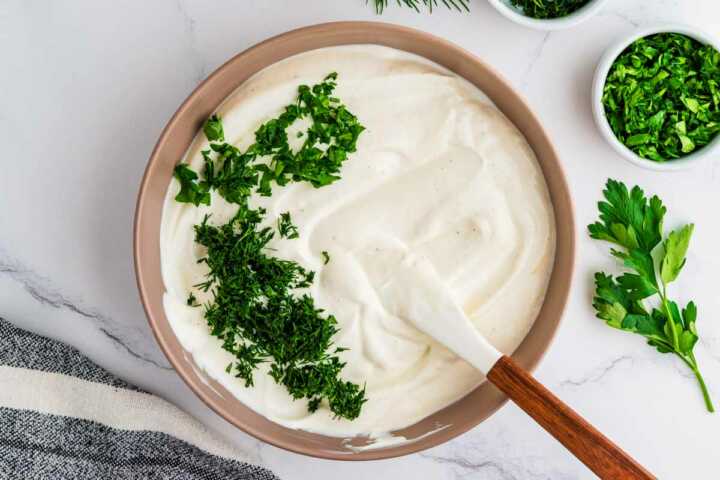 Folding herbs into dill dip.