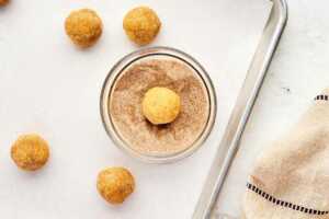 rolling snickerdoodles in cinnamon sugar