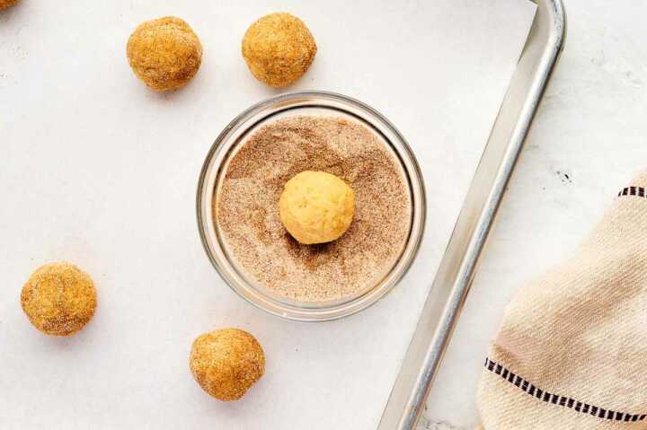 rolling snickerdoodles in cinnamon sugar