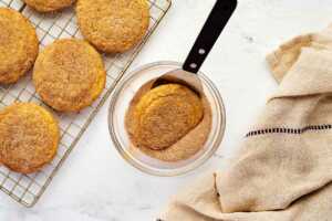 dipping snickerdoodle cookies in cinnamon sugar