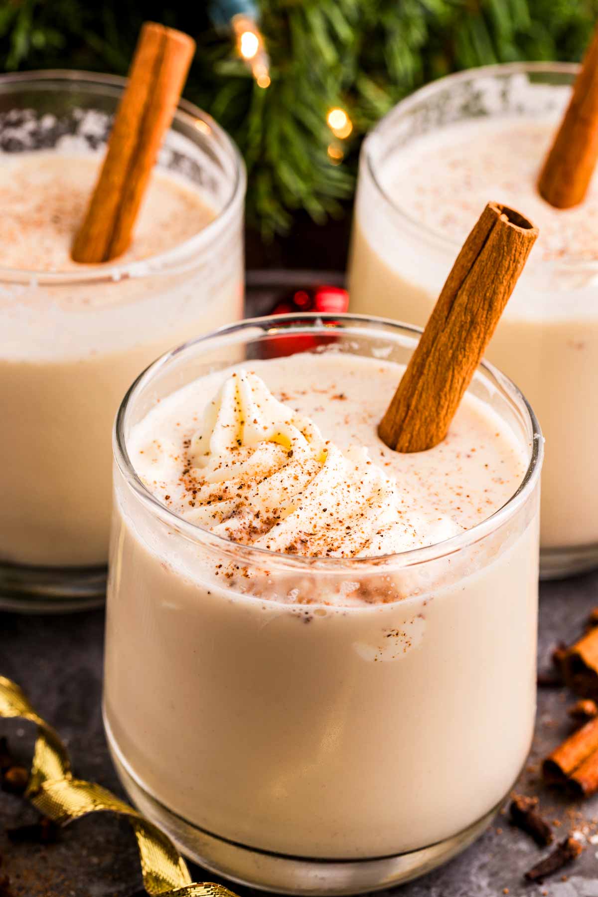 glasses of eggnog in front of a Christmas tree