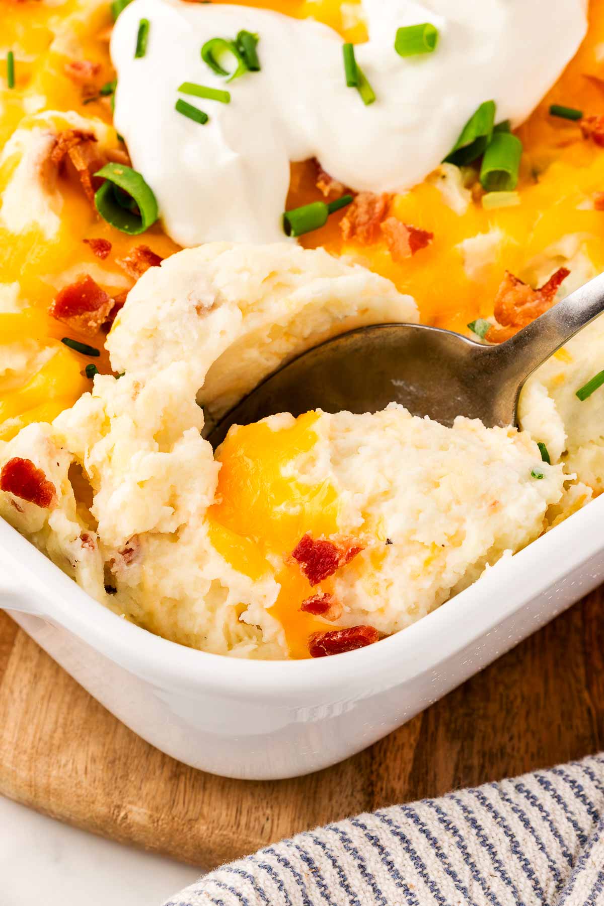 scooping up mashed potato casserole from the dish