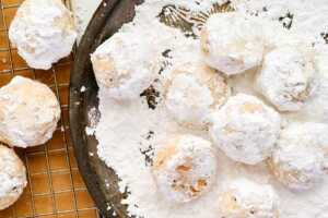 Re-rolling Snowball Cookies in powdered sugar for the perfect finish.