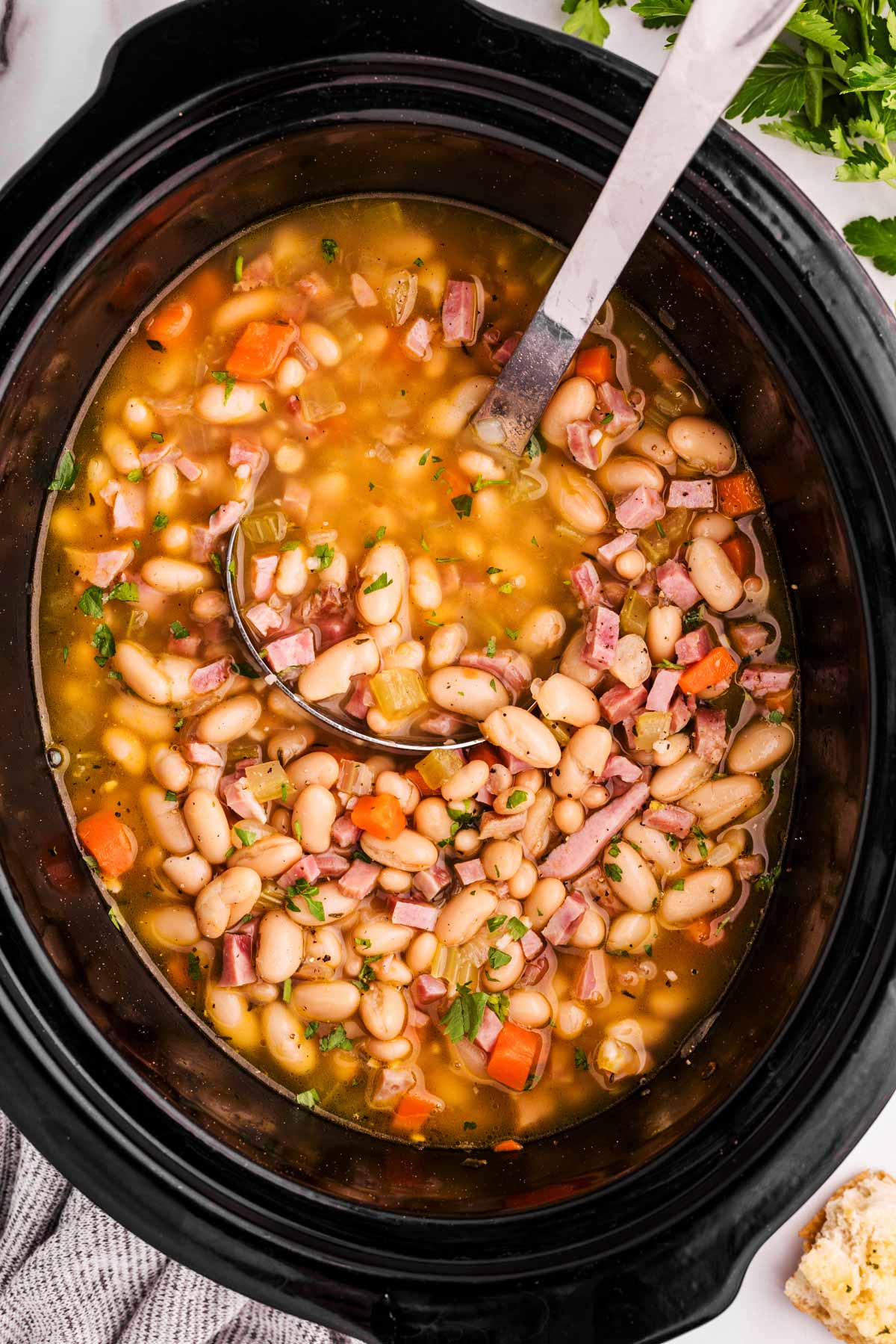 ladling ham and bean soup from a slow cooker