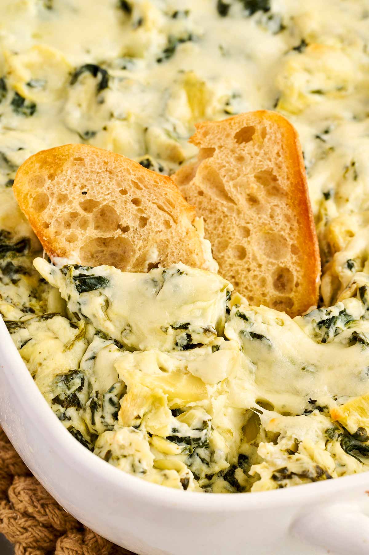 Dipping bread into spinach artichoke dip.