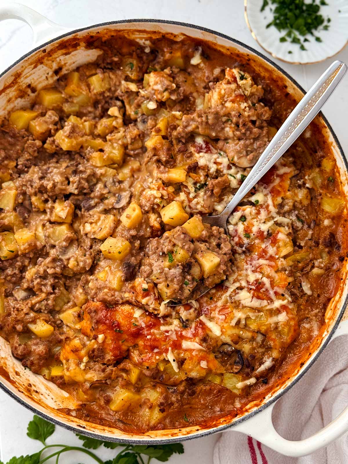 ground beef and potato casserole being served from oven-safe skillet
