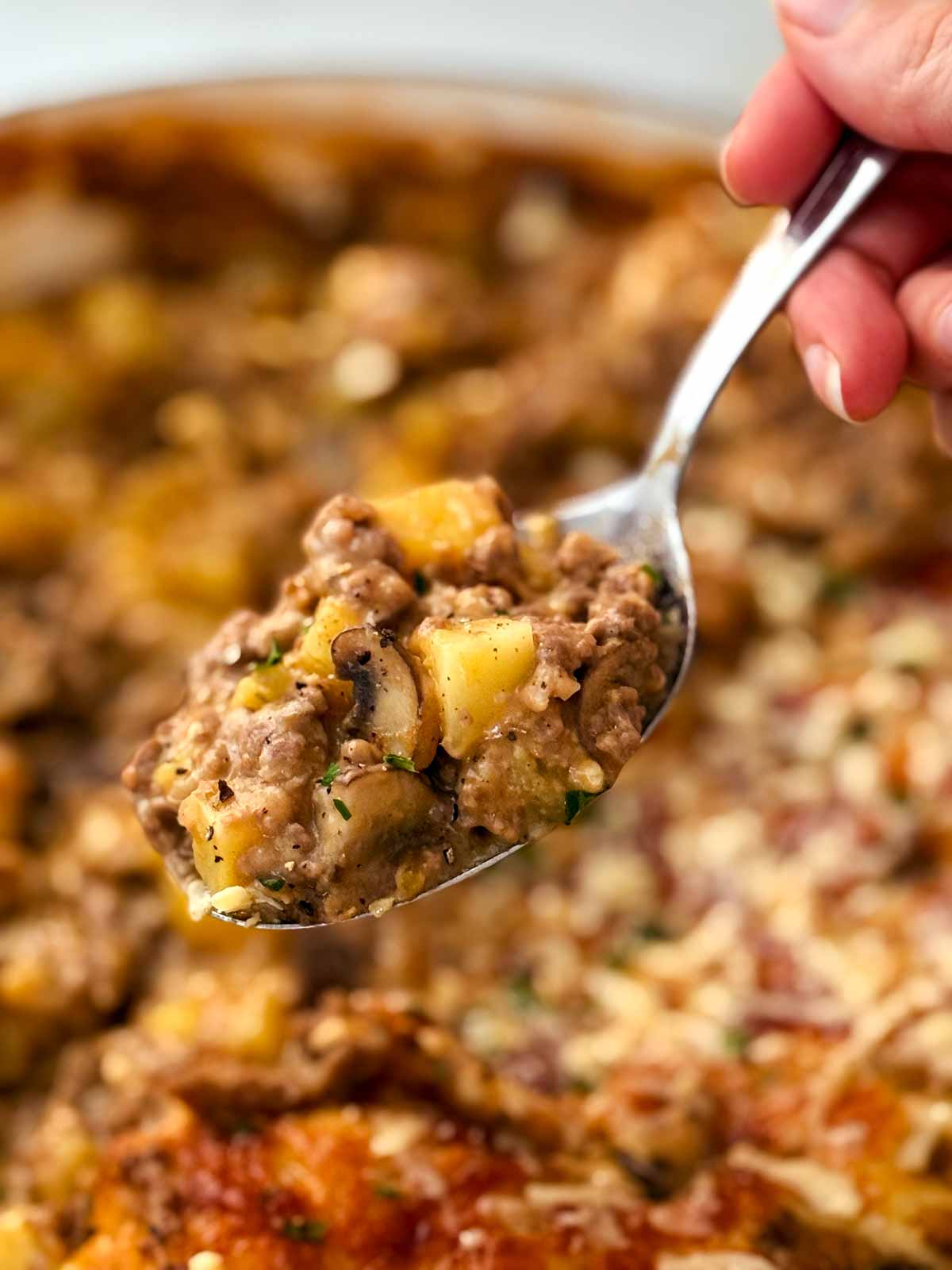 serving ground beef and potato casserole with a spoon