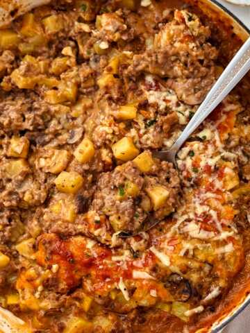 ground beef and potato casserole being served from oven-safe skillet
