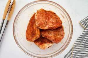 Seasoned pork chops in a bowl.