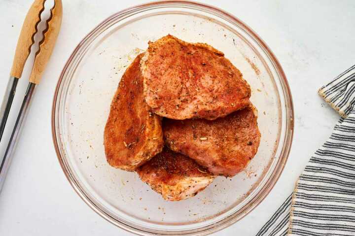 Seasoned pork chops in a bowl.
