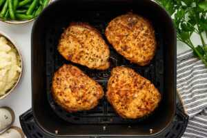Air fried pork chops in an air fryer basket.