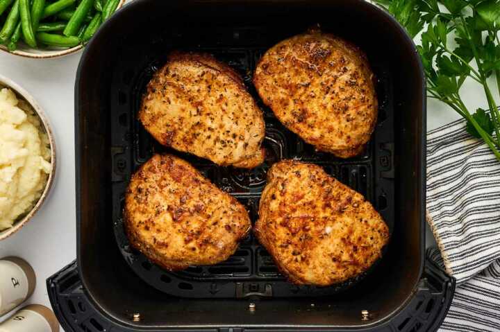Air fried pork chops in an air fryer basket.