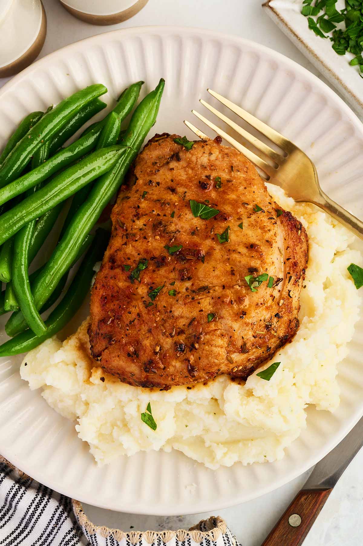 Plating pork chops with mashed potatoes and green beans.