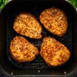 Pork chops in an air fryer basket.