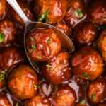 cranberry meatballs being spooned from a slow cooker