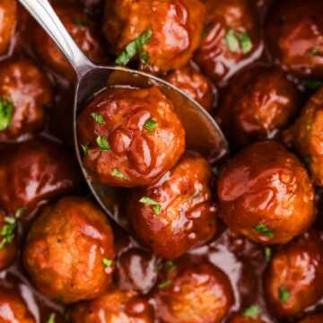 cranberry meatballs being spooned from a slow cooker