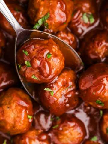 cranberry meatballs being spooned from a slow cooker