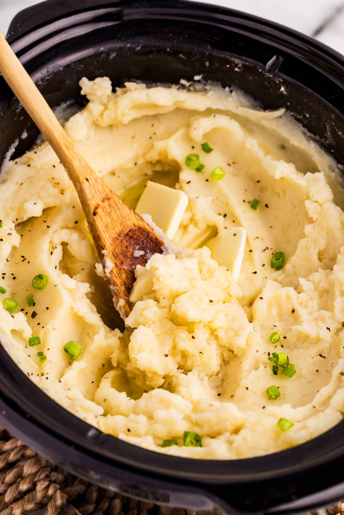 Scooping mashed potatoes from a slow cooker crock.