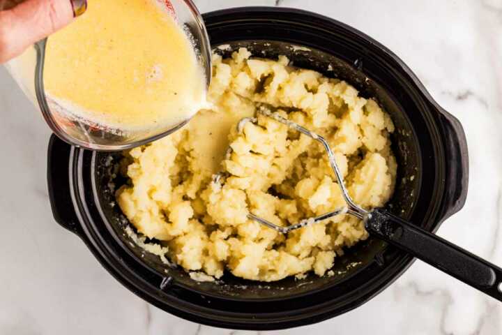 Adding milk to slow cooker mashed potatoes.