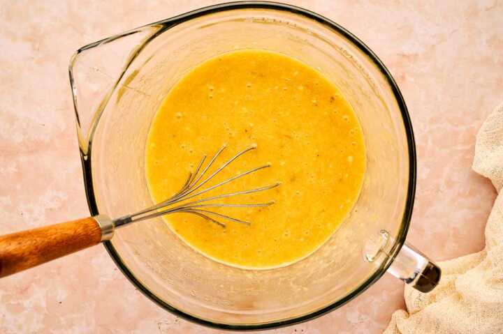 Wet ingredients for banana bread whisked in a bowl.