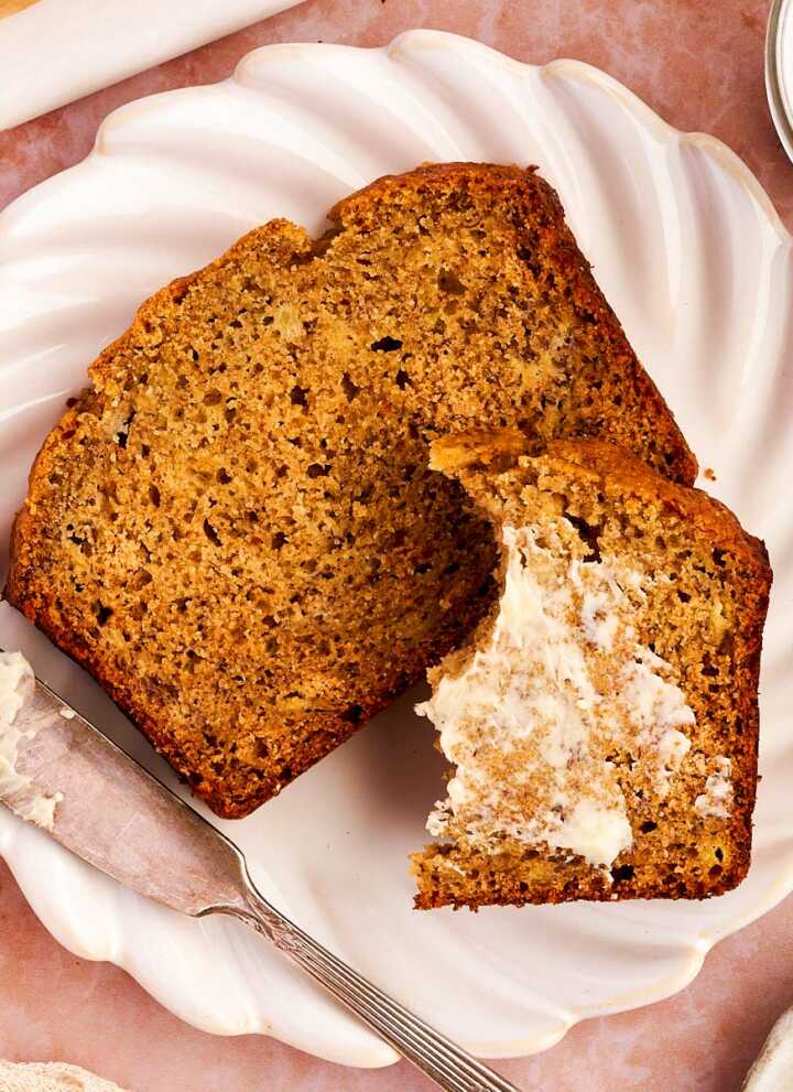 Slice of healthy banana bread on a plate with butter.