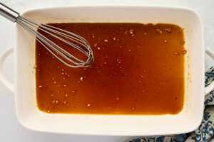 Whisking honey glaze in a casserole dish.