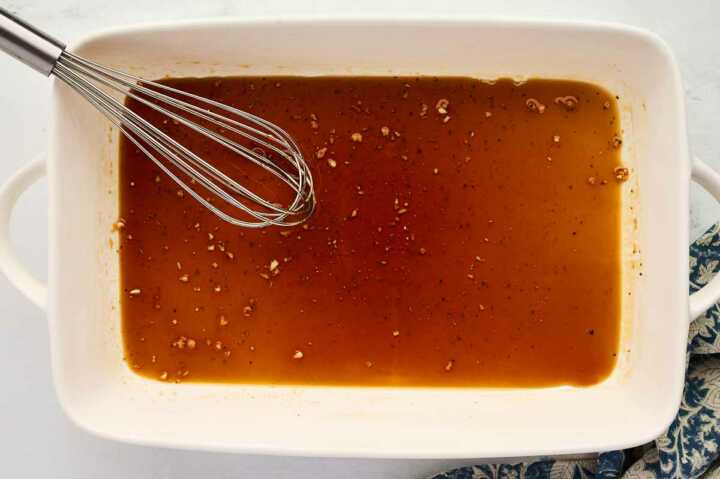 Whisking honey glaze in a casserole dish.