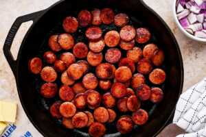 Browned kielbasa rounds in cast iron skillet.