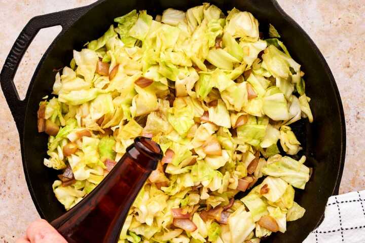 Using a bottle of beer to deglaze a skillet of sautéed cabbage.