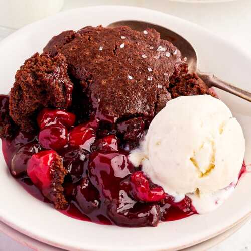 Bowl with chocolate cherry cobbler and a scoop of vanilla ice cream.