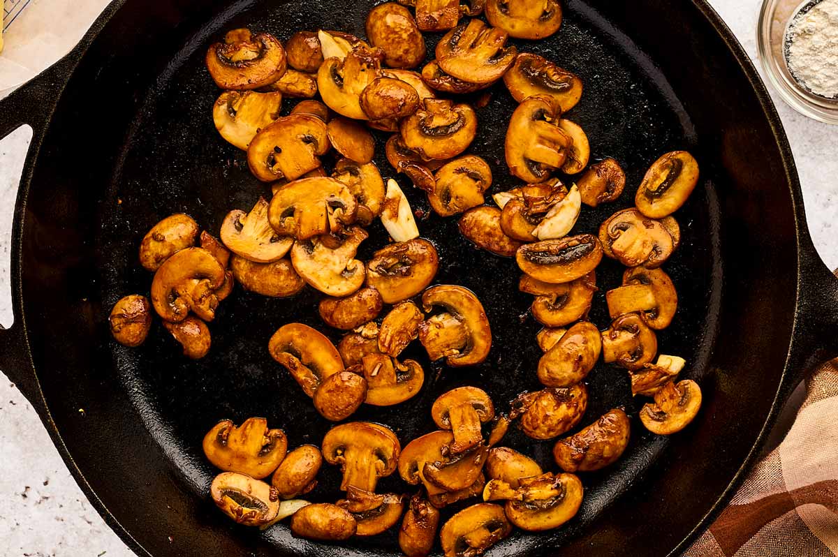 Seared mushrooms in cast iron skillet.