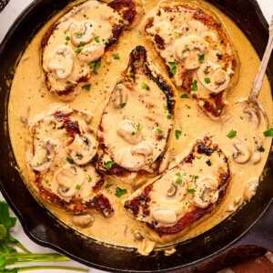 Cast iron skillet with pork chops in creamy mushroom sauce.