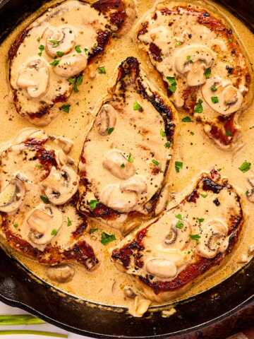 Cast iron skillet with pork chops in creamy mushroom sauce.