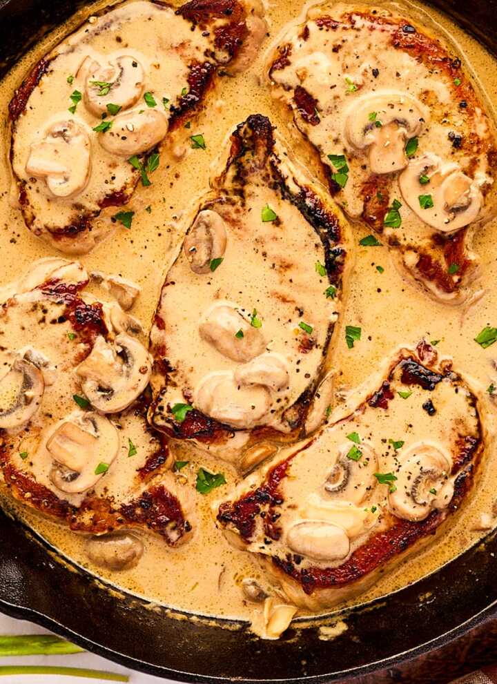 Cast iron skillet with pork chops in creamy mushroom sauce.