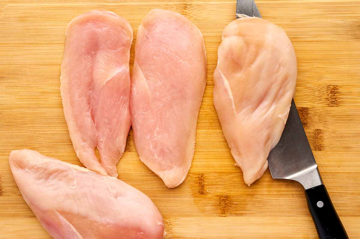 Cutting chicken breast in half.
