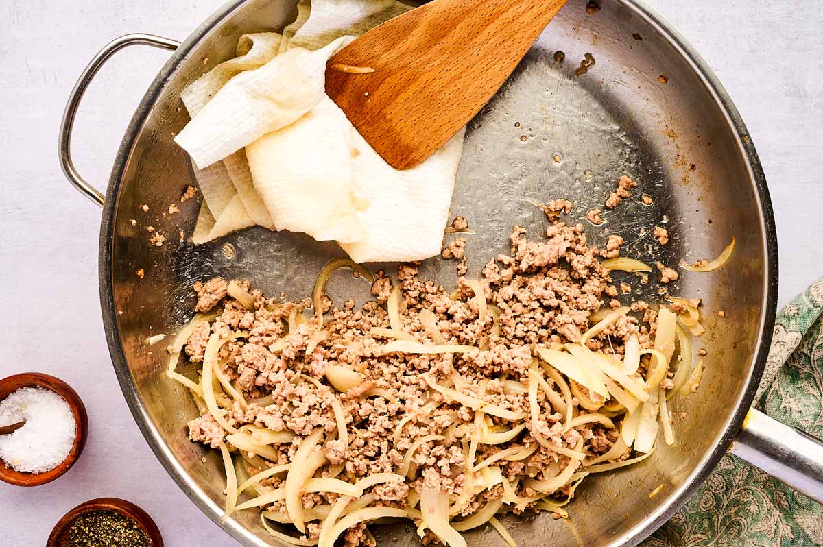 Wiping the skillet while browning ground pork.