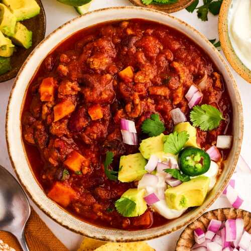 Bowl of turkey chili with toppings.