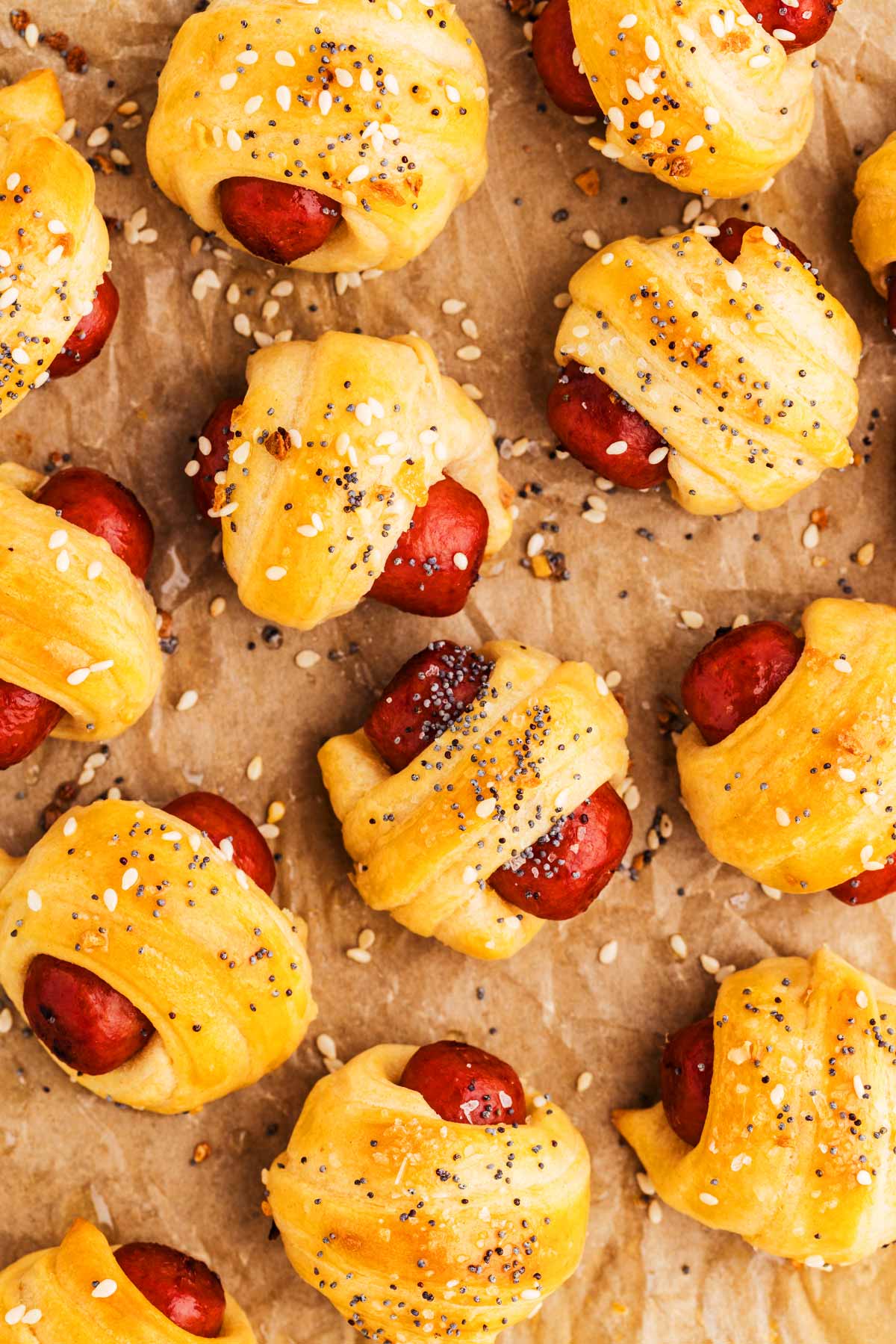 Pigs in blanket on a piece of baking parchment.